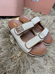 Miu Miu canvas logo slide sandals featuring a neutral ecru fabric upper with brown leather